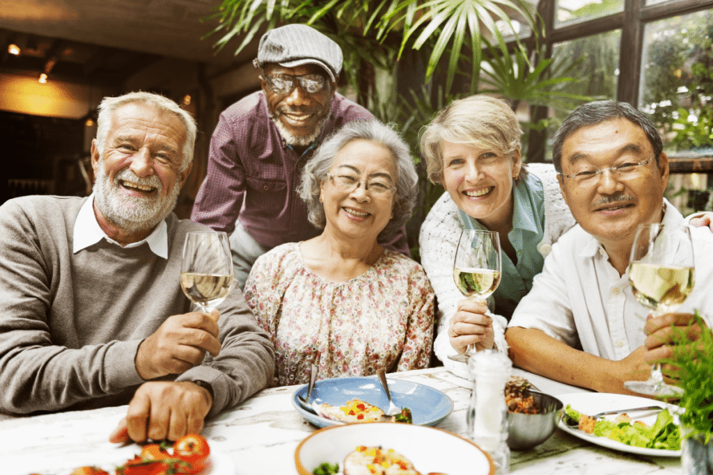 A group of older individuals sitting and posing at the dinner table while smiling.